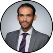 A man in a gray suit, white shirt, and purple striped tie poses for a professional headshot against a light gray background, framed in a circular border.