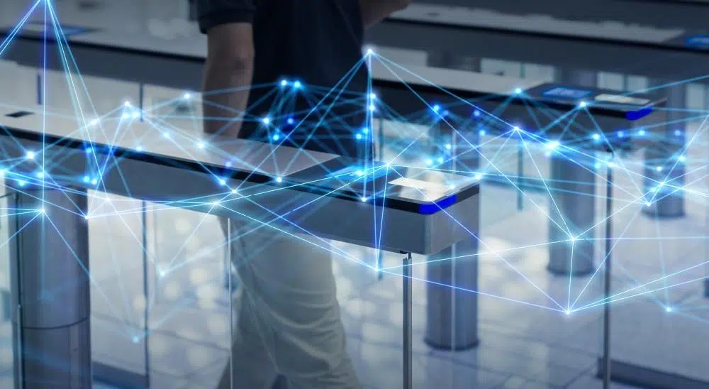 A person walks through electronic security gates, overlaid with a digital network of glowing blue lines and nodes, symbolizing data and smart technology integration.